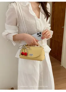 Chic minimalist yellow shoulder bag with pearl bow and cherry charm, stylish crossbody purse for women.