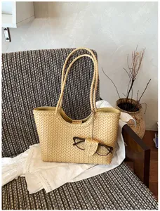 Woven tote bag detail showcasing premium leather texture, double straps, and pouch accessory.