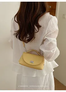 Minimalist yellow shoulder bag with top handle and metal turn-lock detail for women.