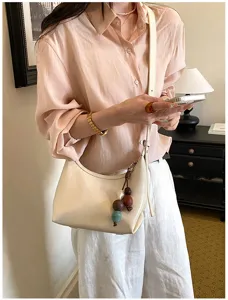 Minimalist off-white underarm shoulder bag for women, chic crossbody bag with cute charm.