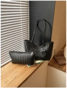 Detailed view of black woven leather tote bag and pouch set, chic daily commute handbag style.