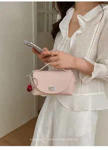 Pink leather shoulder bag with chic silver turn lock and cute cherry charm detail.