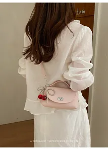 Pink shoulder bag detail with cherry and pearl bow charm, elegant retro style daily wear.