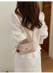 Stylish pink shoulder crossbody bag for women, featuring a top handle and cute charm.