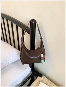 Detailed view of the dark brown minimalist hobo shoulder bag with charming beaded pendant.
