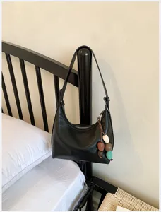 Minimalist black leather underarm shoulder bag for women, chic hobo bag with beaded charm decor.