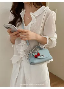 Trendy light blue leather crossbody bag with chic cherry charm and elegant chain design.