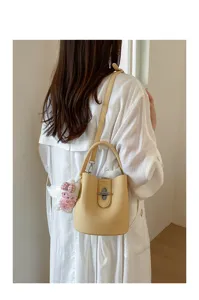 Vue de détail du sac seau jaune élégant mettant en valeur son cuir texturé et son fermoir.