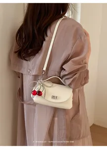 Chic white leather shoulder bag featuring a cute cherry pearl bow pendant and sleek metal lock.