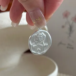 Scatto di dettaglio di un ciondolo in argento opaco vintage con rosa in rilievo e LOVE.