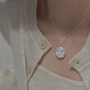 Primo piano dettagliato della collana con ciondolo a rosa opaca retrò in argento.