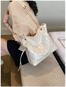 Detailed view of the elegant quilted tote bag with chain strap and soft beige shiny finish.