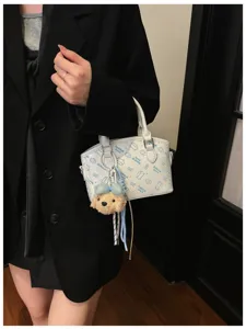 Korean style white PU leather crossbody handbag with cute cartoon print and plush toy.