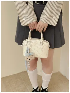 Detailed view of the cute beige mini bucket bag with embossed cartoon prints and plush bear.