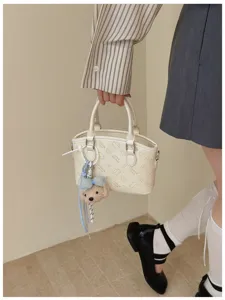 Detail view of a stylish cream PU leather bucket handbag with cute cartoon embossed patterns.