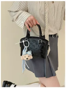 Detailed view of a chic black leather handbag with embossed patterns and cute plush puppy charm.