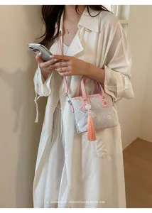 Schicke, neue chinesische Umhängetasche mit eleganter Quaste und rosa Griffen für den Alltag.
