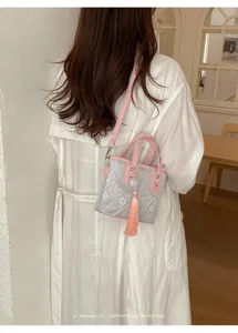 Detailansicht der neuen chinesischen rosa grauen Handtasche mit elegantem Quastenanhänger.
