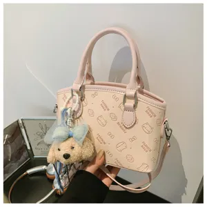 Close-up detail of the cute pink handbag with plush puppy charm and embossed bow patterns.