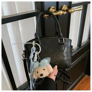 Black PU leather handbag with cute plush pendant and embossed cartoon cat pattern for women.