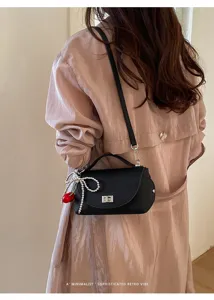 Chic black shoulder bag for women, elegant pearl bow and cherry pendant, retro minimalist style.