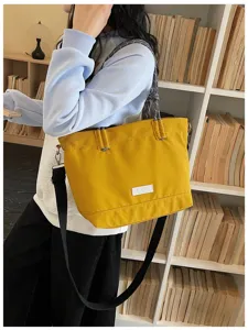 Detail view of yellow canvas tote bag with shoulder strap and stylish rope handle for daily use.