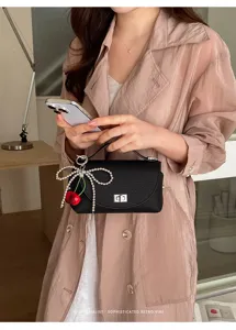 Stylish women's black top-handle shoulder bag with pearl bow and cherry charm.