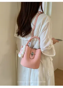 Vue détaillée du sac seau rose en cuir grainé avec fermoir tournant métallique et pendentif.