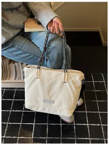 Canvas tote bag detail showing thick woven rope handles and off-white fabric texture.
