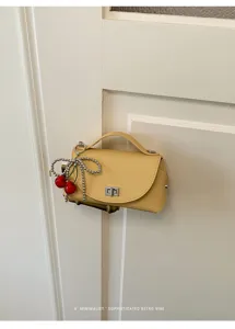 Chic yellow PU leather shoulder bag with cute cherry bow charm and turn-lock closure for women.