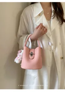 Vue détaillée d'un sac seau rose pour femme en cuir texturé avec un joli pendentif en peluche.