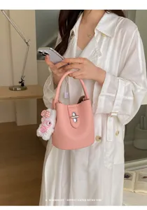 Gros plan détaillé du sac seau rose élégant avec texture grain de litchi et fermoir métallique.