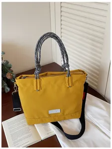 Casual yellow tote bag detail featuring durable fabric, grey rope handles and shoulder strap.