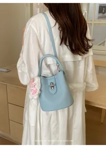 Vue detaillee d'un sac seau chic en cuir bleu clair avec fermoir tournant et peluche.