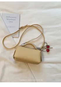 Detailed view of the chic apricot shoulder crossbody bag with cute cherry charm closeup.