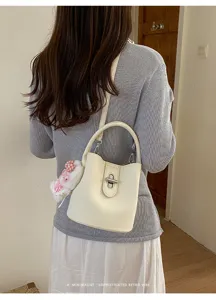 Sac seau minimaliste chic pour femme, sac bandoulière en cuir grainé avec verrou métallique.