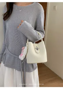 Sac seau élégant pour femmes avec pendentif en peluche et fermoir chic pour un usage quotidien.