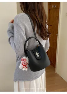 Sac seau en cuir noir avec charm en peluche mignon, sac bandoulière polyvalent pour femmes.