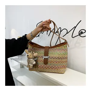 Gewoven stro bucket bag met kleurrijk chevron patroon, bruine lederen riem en schattige berenhanger.