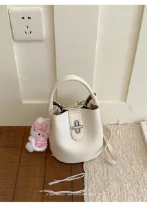 Vue détaillée du sac seau minimaliste en cuir blanc avec joli pendentif lapin.