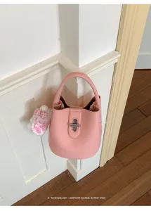Vue détaillée d'un sac seau rose en cuir texturé avec serrure en métal et pendentif lapin.