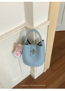 Sac seau minimaliste en cuir bleu avec poignée et détail de serrure en métal.