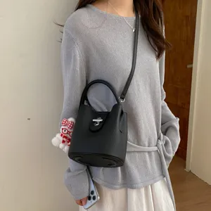 Sac seau noir élégant en cuir synthétique grainé avec fermeture métallique pour femmes.