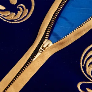 Blue velvet jacket detail showing gold embroidery and metallic zipper craftsmanship.