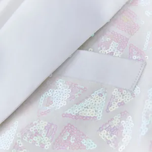 Close-up detail of men's white sequin suit jacket featuring iridescent triangular pattern.