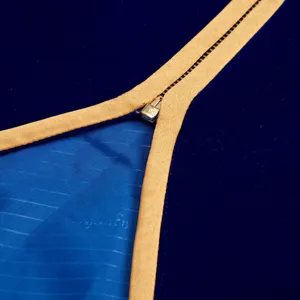 Close-up detail of royal blue velvet jacket with gold trim and metal zipper craftsmanship.