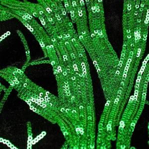 Λεπτομερές κοντινό πλάνο από ζωντανό πράσινο ύφασμα με παγιέτες σε μαύρο φόντο για σακάκι.