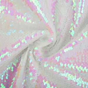 Detailed close-up view of shiny iridescent pink white sequin fabric material for garments.