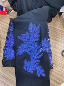 Detalle de pantalón de traje negro para hombre con bordado de aplicación de lentejuelas azules.