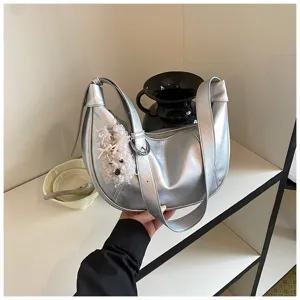 Primo piano dettagliato di elegante borsa a tracolla hobo metallizzata argento con ciondolo.